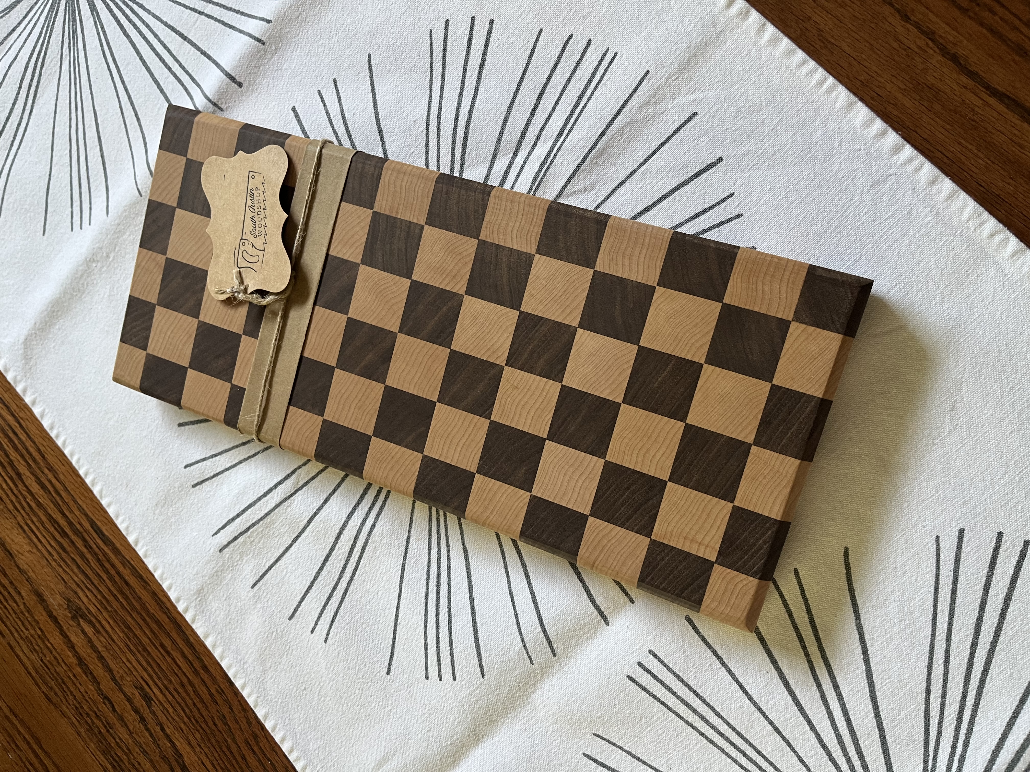 End-grain checkerboard cutting board wrapped with South Austin Woodshop tag