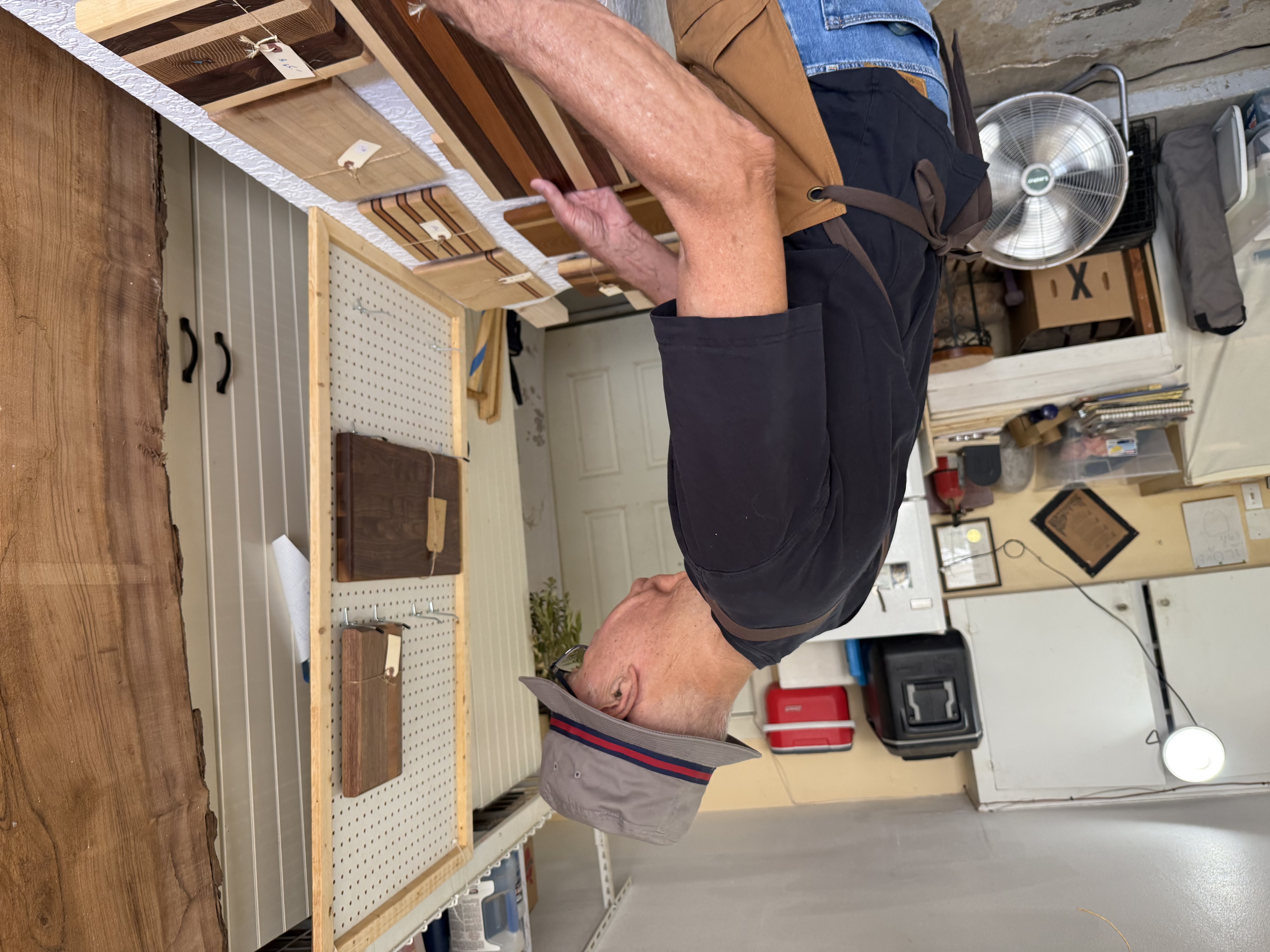 Buzz Pruitt at work in his garage shop, setting up a display of cutting boards