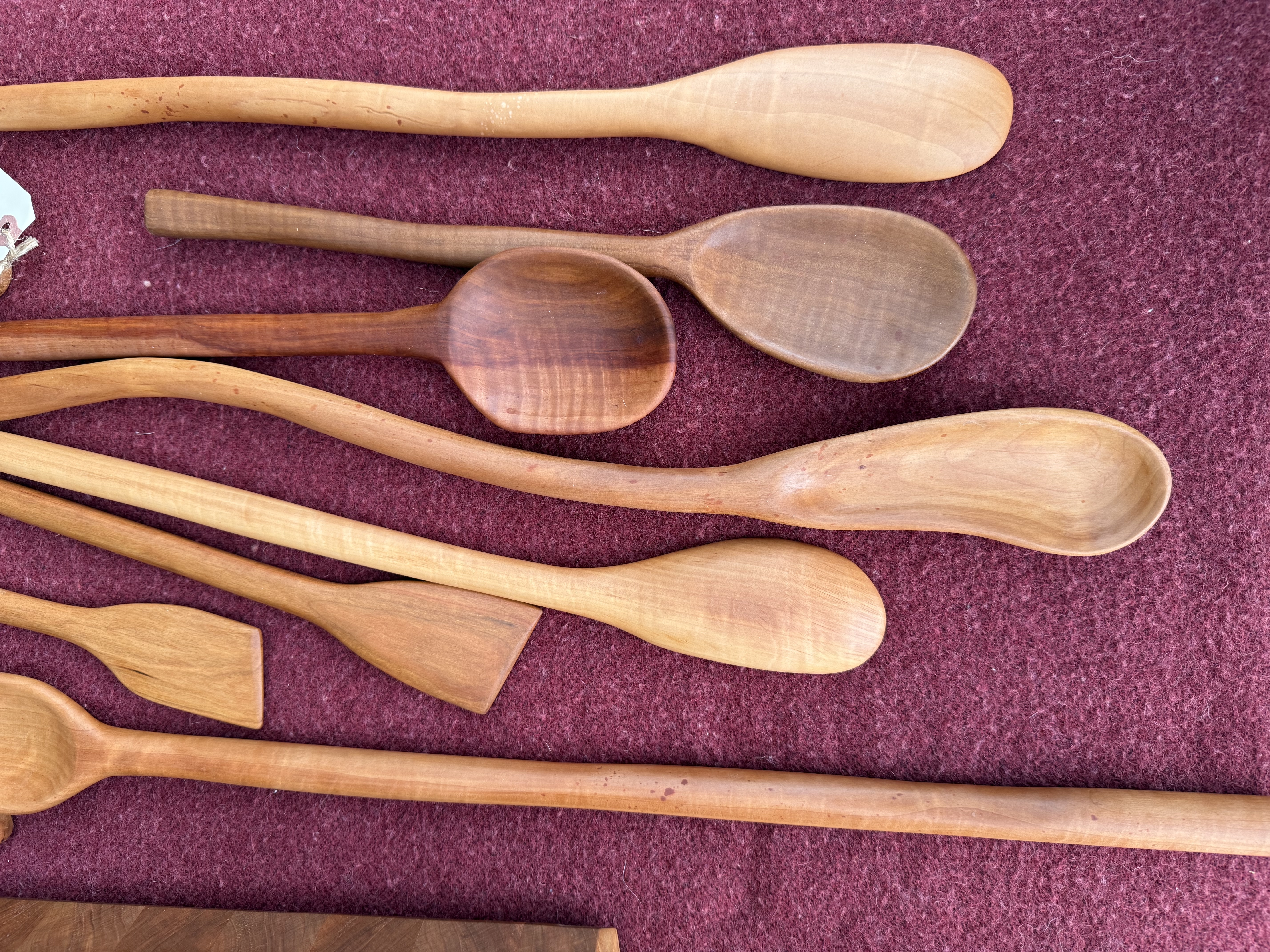 Hand-carved wooden spoons in cherry and walnut grouped on burgundy felt