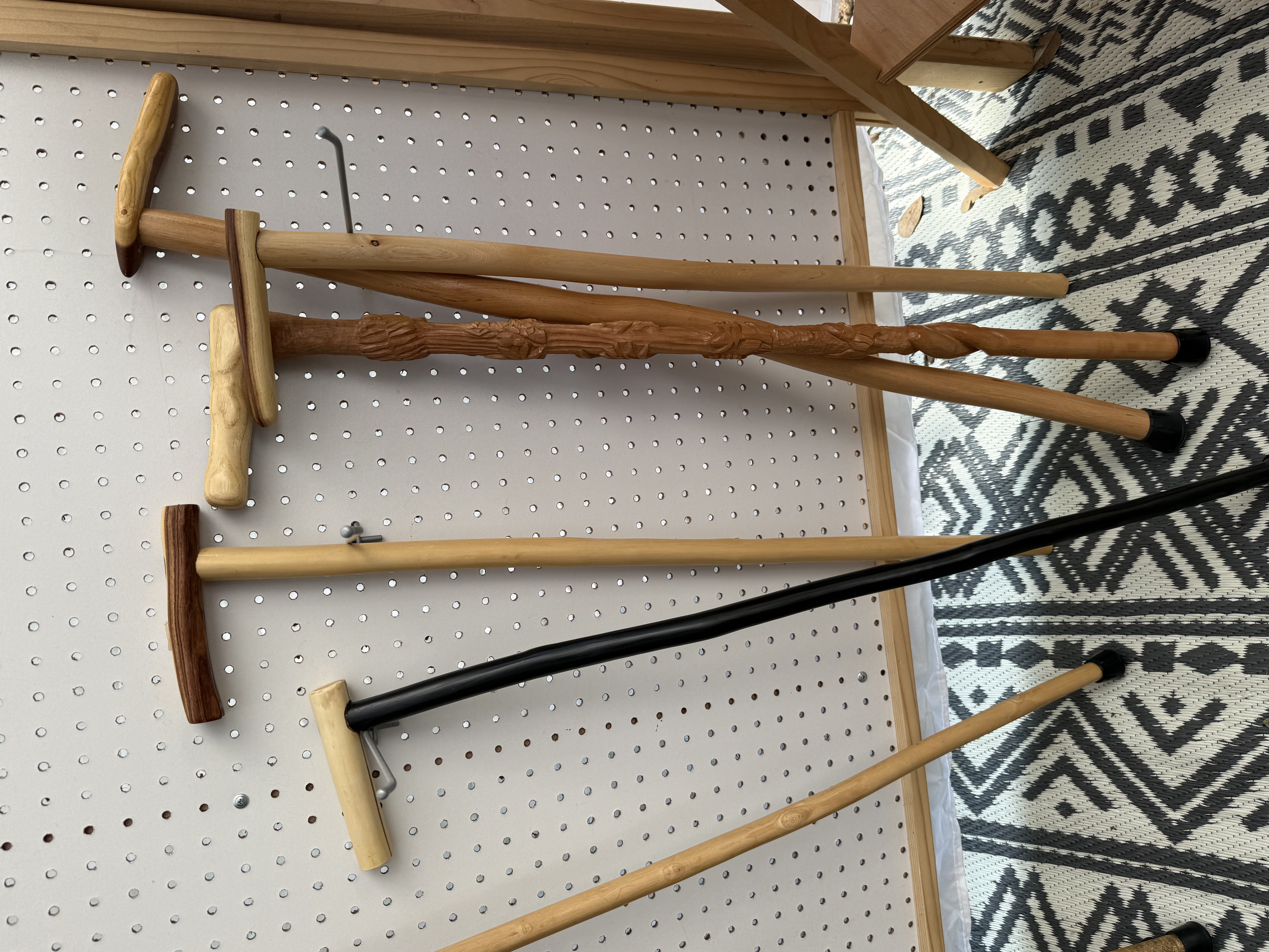 Hand-carved walking sticks leaning against a pegboard