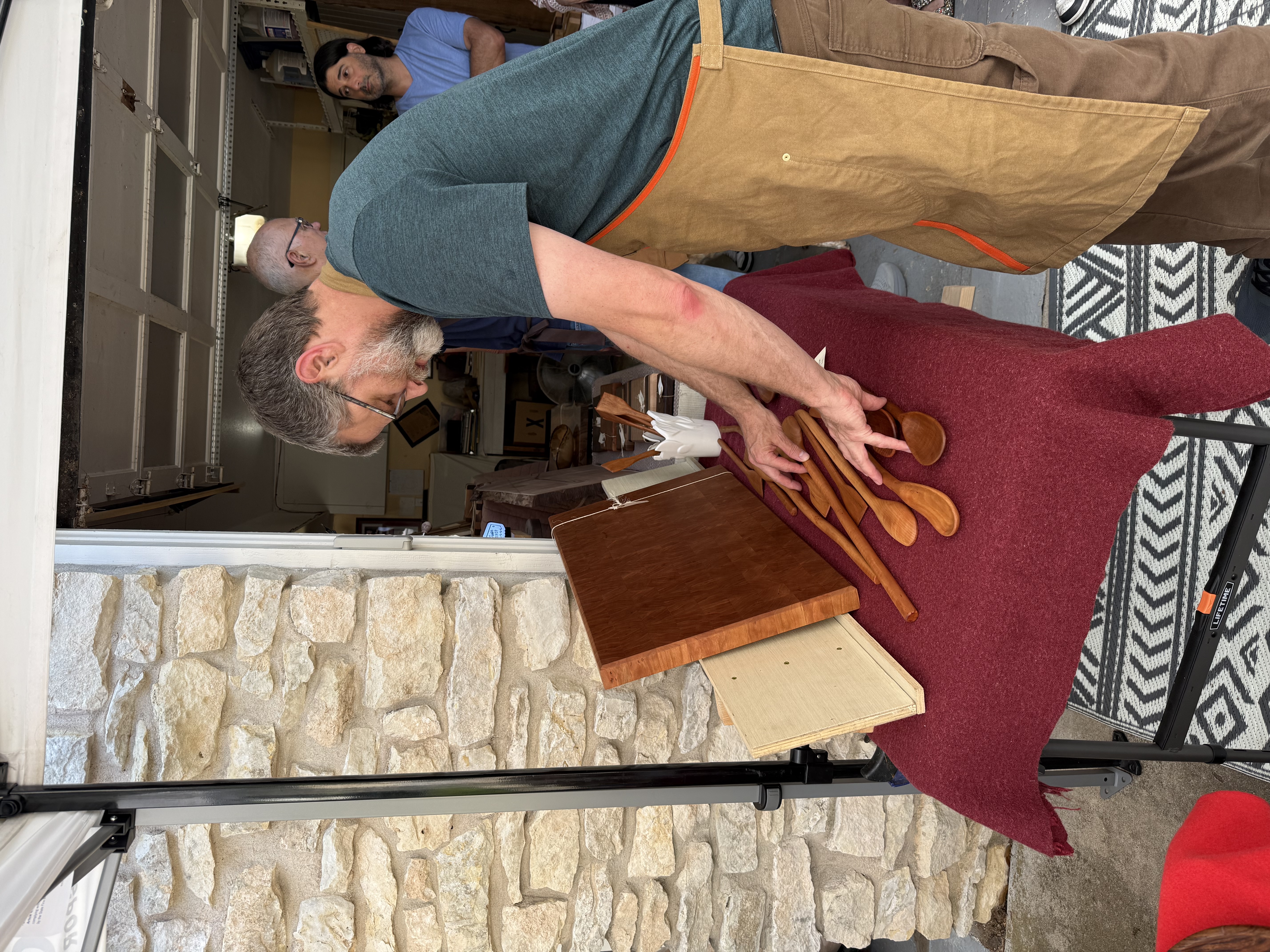 John arranging carved spoons on the table at his booth